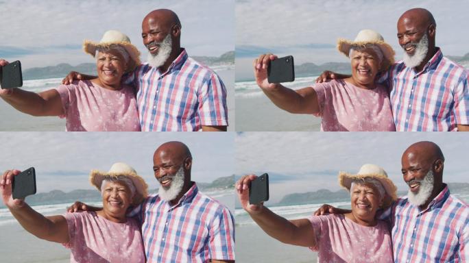 一对混血儿老年夫妇在海滩上用智能手机自拍