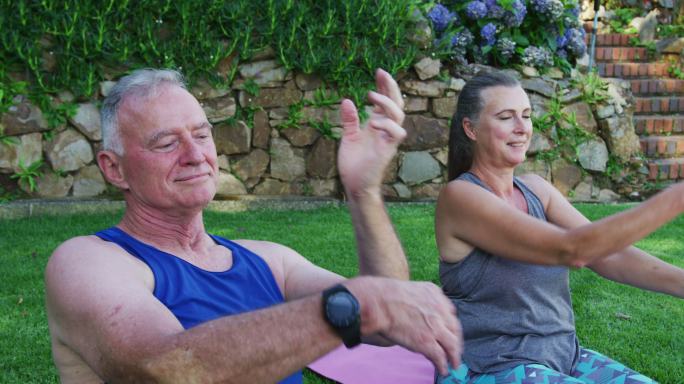 一对白人老年夫妇在花园里一起做伸展运动