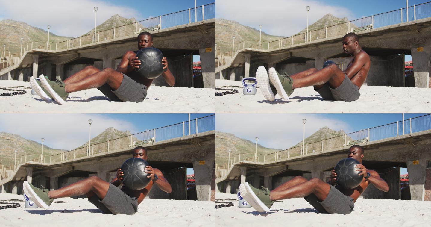 专注的非洲裔美国人做扭转球，在户外海滩锻炼
