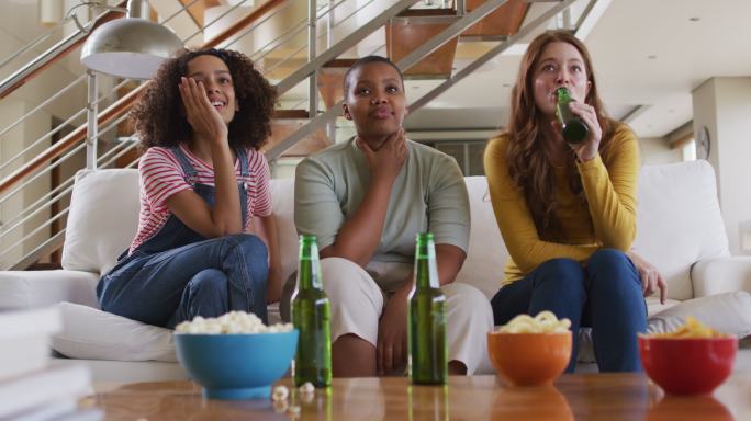 各种各样的女性朋友在家里喝啤酒看电视