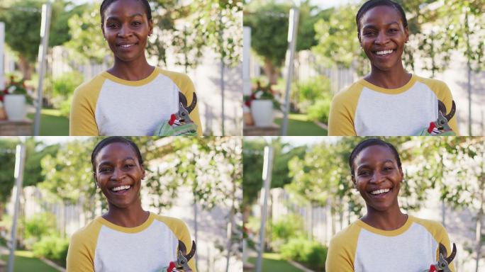 非裔美国妇女的肖像，拿着剪报看着相机和微笑在花园里