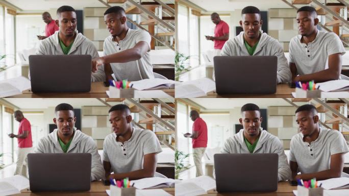 一对非洲裔美国青少年双胞胎兄弟一边用笔记本电脑一边和父亲聊天