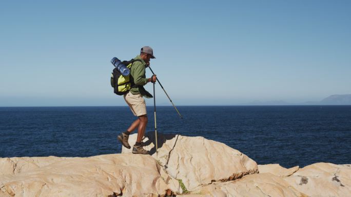 非洲裔美国人在海边的乡下用登山杆徒步旅行
