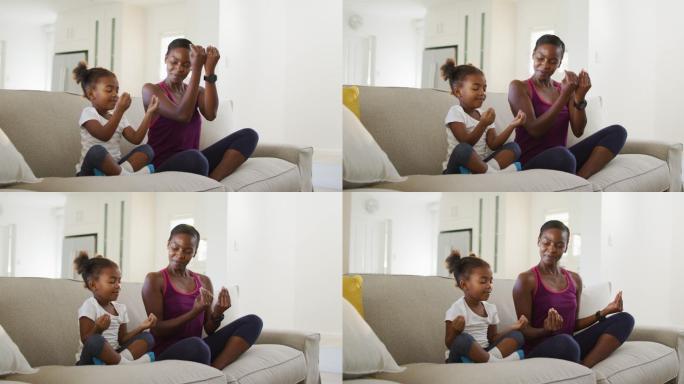 快乐的非裔美国母亲和女儿坐在沙发上做瑜伽练习在家里