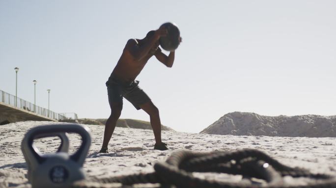 一个非洲裔美国人在沙滩上用健身球锻炼