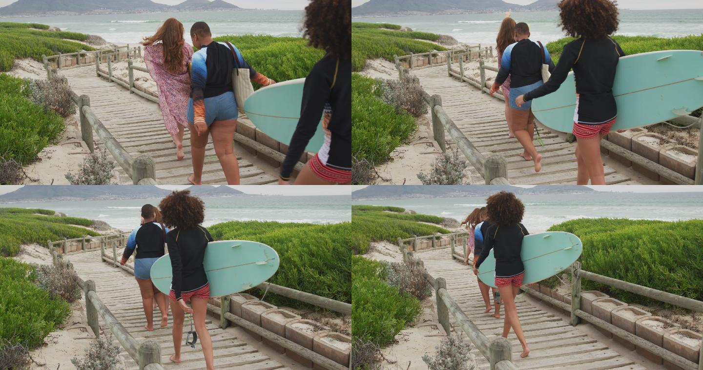 各式各样的快乐女性朋友们手拿冲浪板去海滩