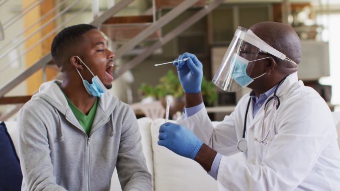 非裔美国资深男医生戴着口罩为家中男患者进行covid - 19检测