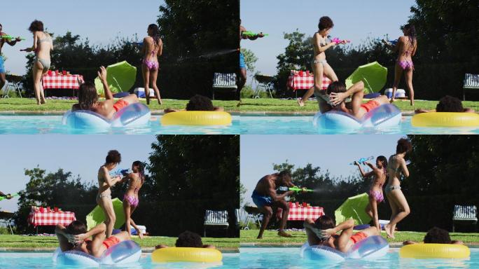 混合种族的女人玩水枪在游泳池里