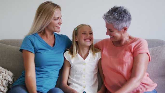 白种人的祖母，母亲和女儿坐在家里的沙发上微笑