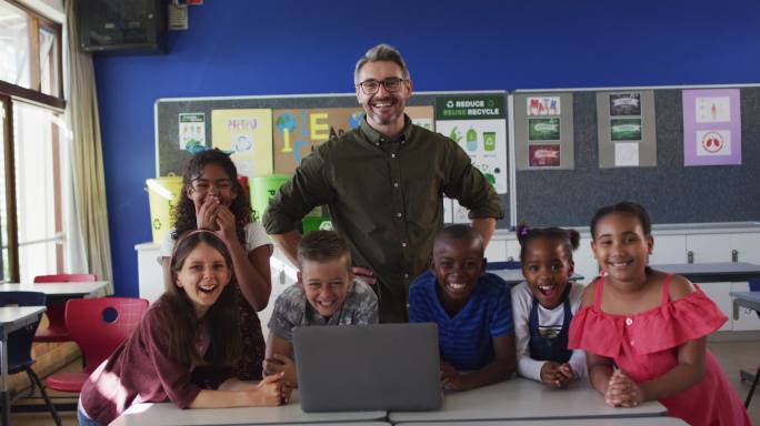 快乐的不同男老师和一群孩子看着笔记本电脑的肖像