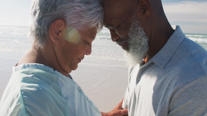 一对非洲裔美国老夫妇在海滩上摸着对方的额头