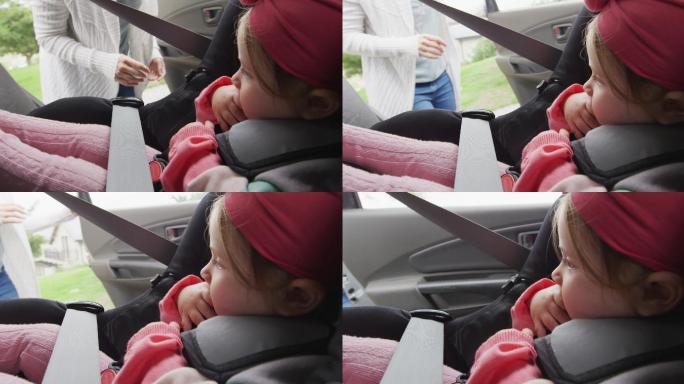 白人母亲把孩子放在车里的安全座椅上，然后关门
