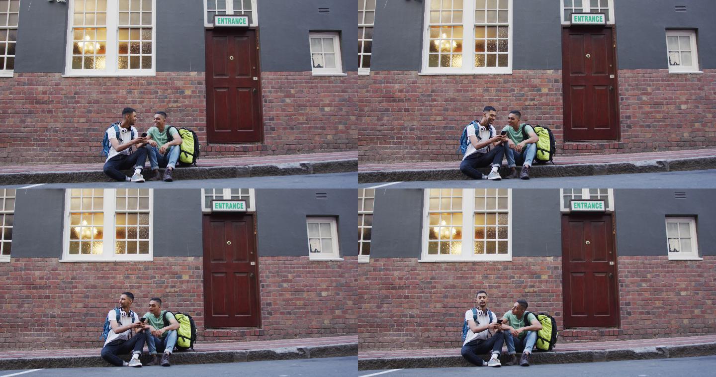 两个混血男性朋友在街上坐着、聊天、使用智能手机