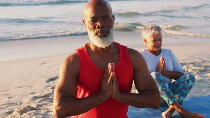一对非洲裔美国夫妇在海滩上练习瑜伽