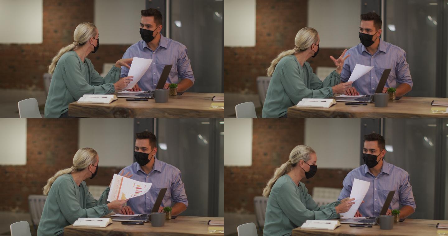 白种男性和女性的商业同事戴着口罩在工作中讨论