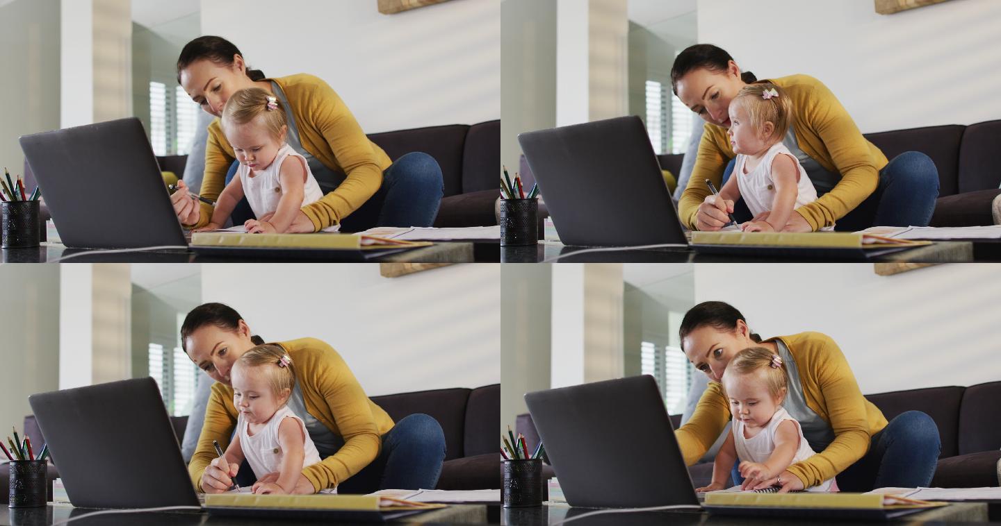 一位抱着孩子在家工作的白人母亲在做笔记