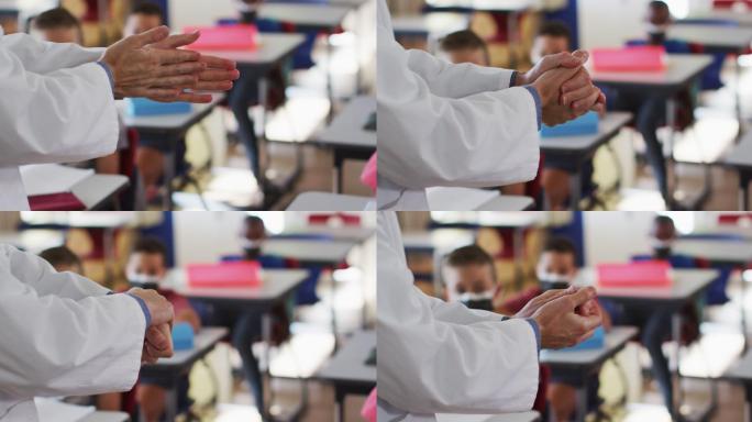 教师在教室里为双手消毒，学生戴着口罩坐在教室里
