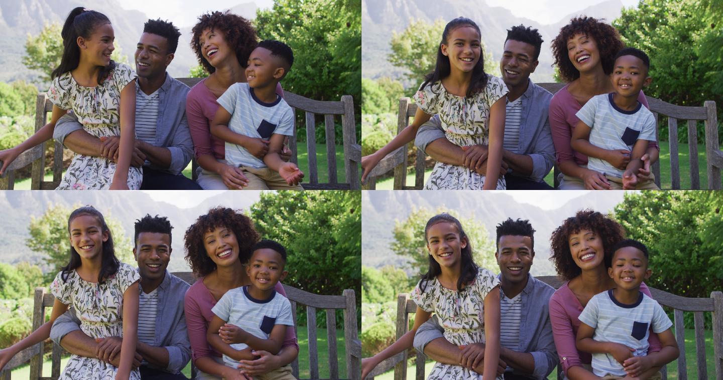快乐的非裔美国父母，女儿和儿子坐在户外的长凳上
