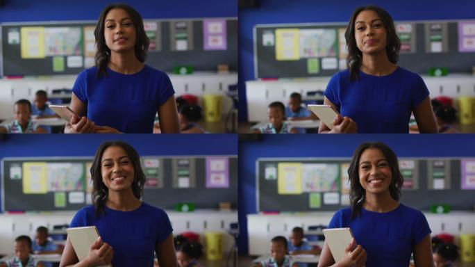 快乐的混血女教师的肖像站在教室里，背景是平板电脑的孩子们
