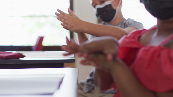 多名学童戴口罩坐在教室里消毒双手
