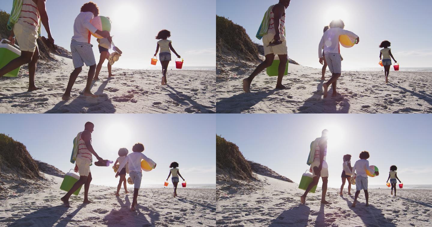 非洲裔美国人的父母和他们的孩子在海滩上带着海滩设备散步