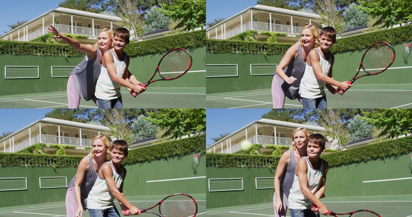 一个白人母亲在一个阳光明媚的日子在网球场教她的儿子打网球