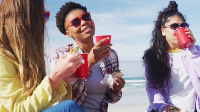 快乐的一群不同的女性朋友在海滩上玩得开心，野餐