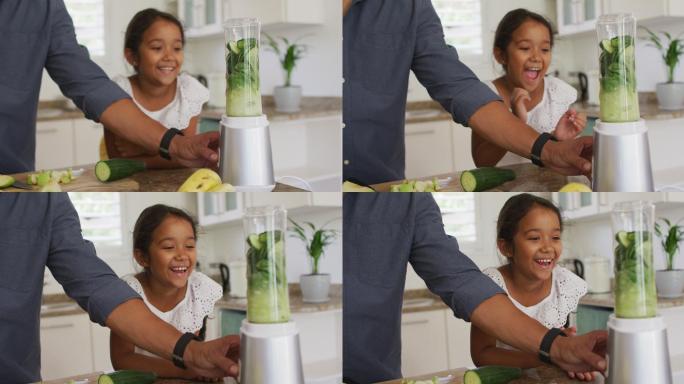 西班牙裔父亲带着微笑的女儿教她如何用搅拌机制作冰沙