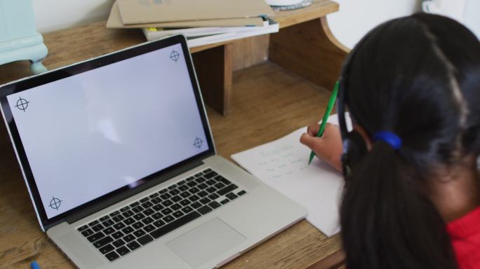 混血儿女孩在家在线学校课堂，使用耳机和笔记本电脑与屏幕上的复制空间