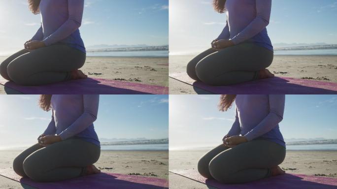 一个混血儿女人在沙滩上的瑜伽垫上冥想