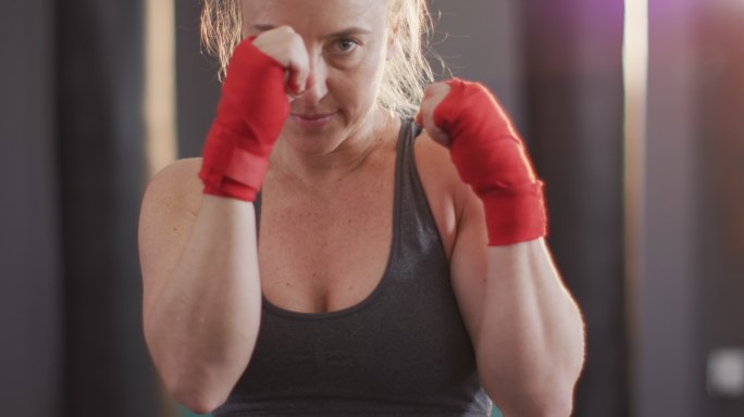 近距离的白人女拳击手练习她的拳击在健身房