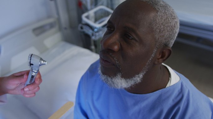 白人女医生在医院检查非洲裔美国老年男性病人的喉咙