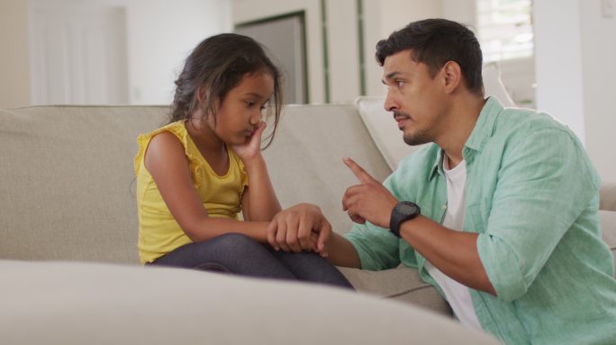 西班牙裔父亲责骂坐在沙发上心烦意乱的女儿