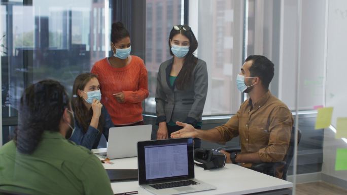 不同组别的同事戴着口罩在会议室讨论