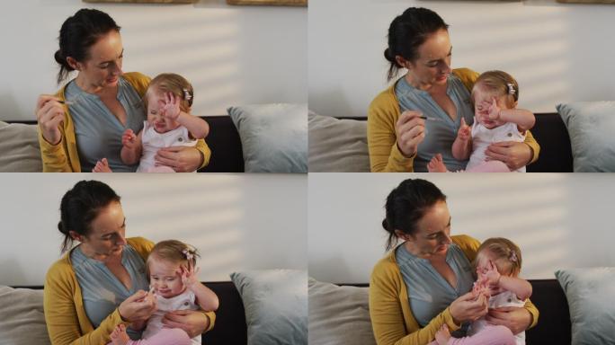 一位白人母亲在家用体温计测量婴儿的体温