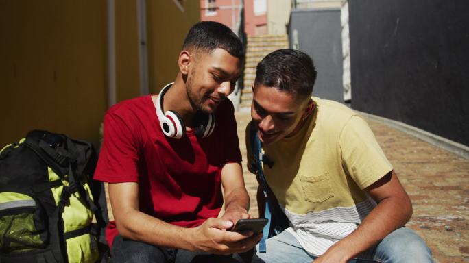 两个混血朋友坐在街上玩智能手机