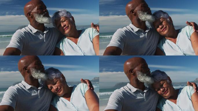 快乐的老非洲裔美国夫妇坐在沙滩上拥抱