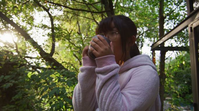 亚洲女孩喝茶在花园和微笑