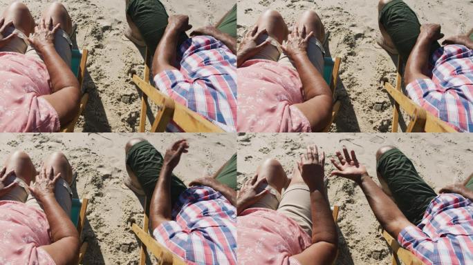 老年非洲裔美国夫妇坐在沙滩上，手牵着手