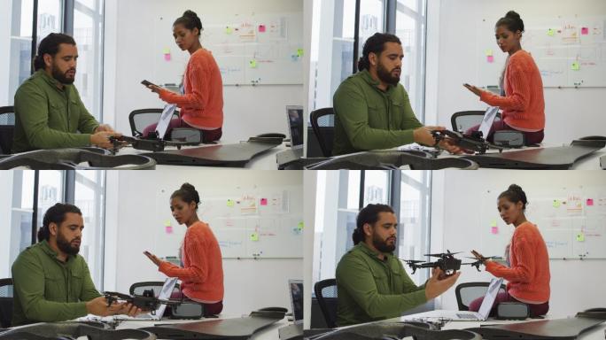 混合种族的男性和女性商业同事持有无人机和平板电脑在会议室