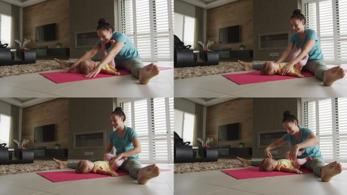 一位白人母亲在瑜伽垫上练习瑜伽时抱着孩子玩耍