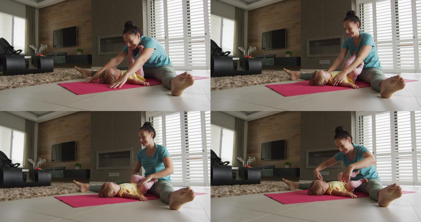 一位白人母亲在瑜伽垫上练习瑜伽时抱着孩子玩耍
