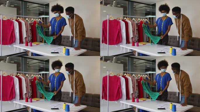 非裔美国男性和女性时装设计师戴着口罩在工作讨论