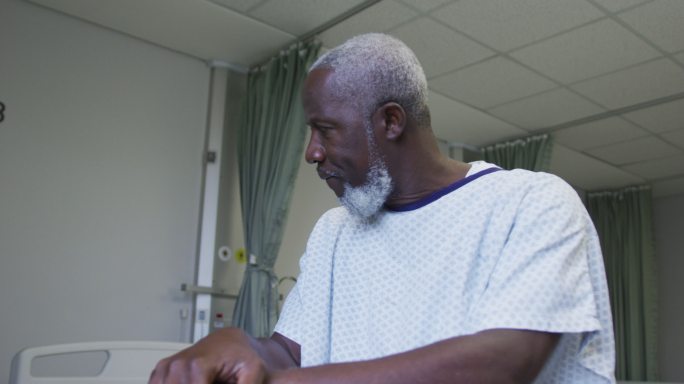 非裔美国男性病人在病房拿着拐杖看窗户