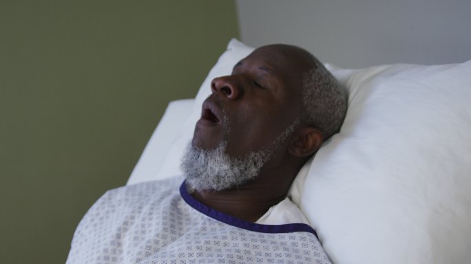 非裔美国男性病人躺在医院病床上打哈欠