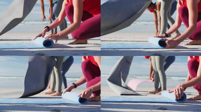 一群不同类型的女性朋友在沙滩上练习瑜伽后滚动瑜伽垫