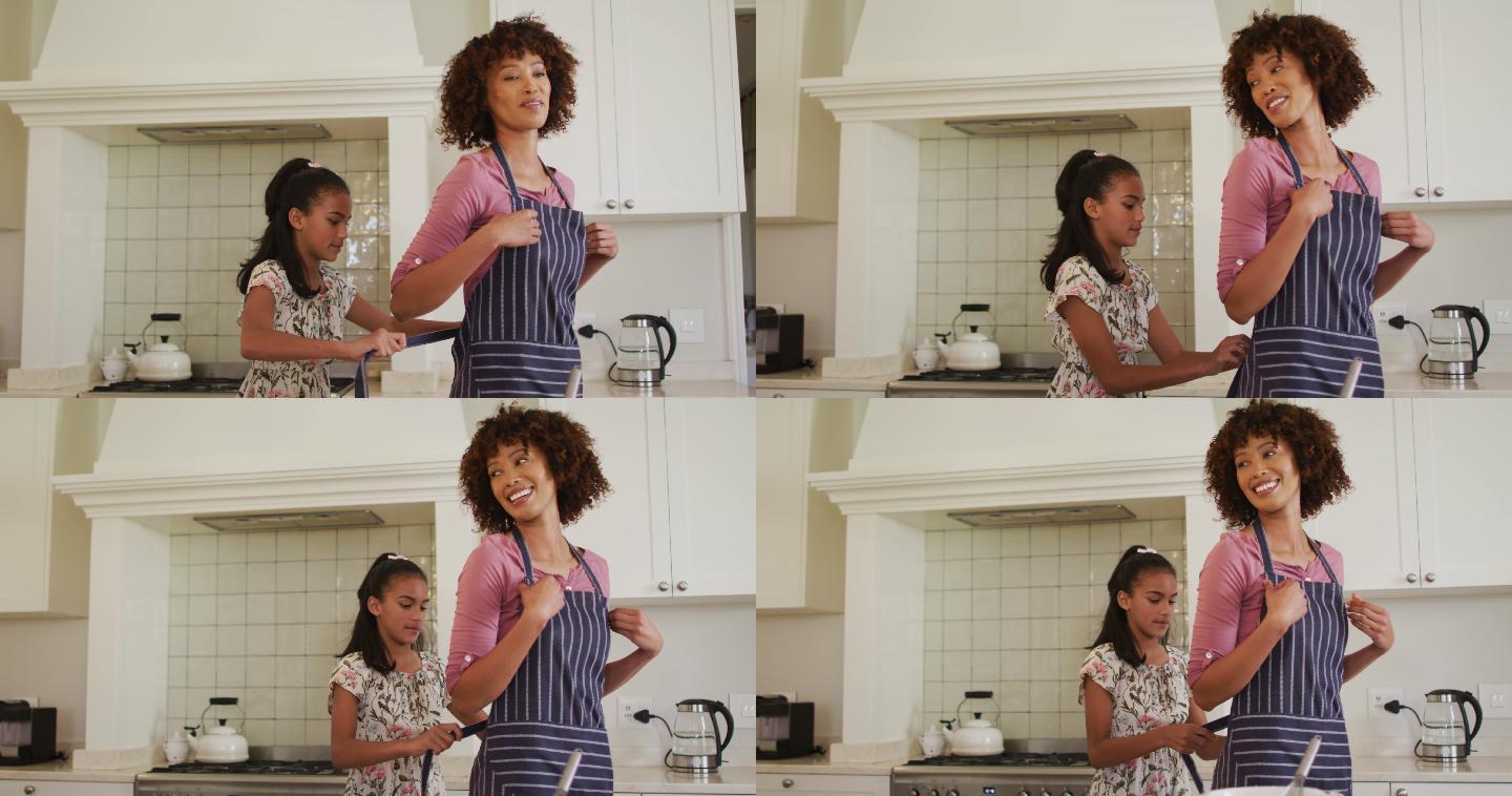 非裔美国女孩在家里的厨房给她妈妈系围裙