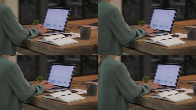白人女商人坐在桌子前用笔记本电脑制作统计报告