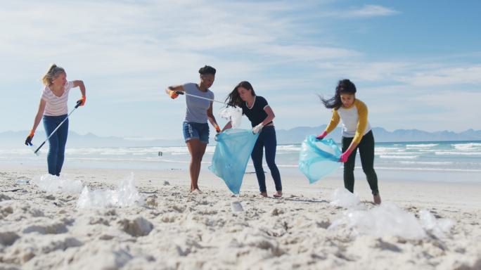 一群女性朋友在海滩上用垃圾袋扔垃圾
