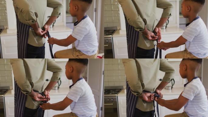 一个非裔美国男孩在家里的厨房里给他的父亲系围裙